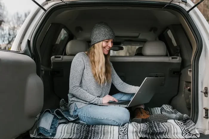  woman in gray sweater and blue denim jeans sitting on car seat small