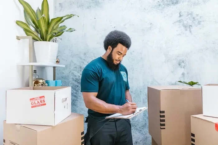  a man in blue shirt writing on a clipboard near parcels small