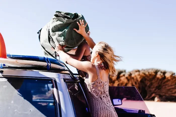  women throwing bag on roof of car copy