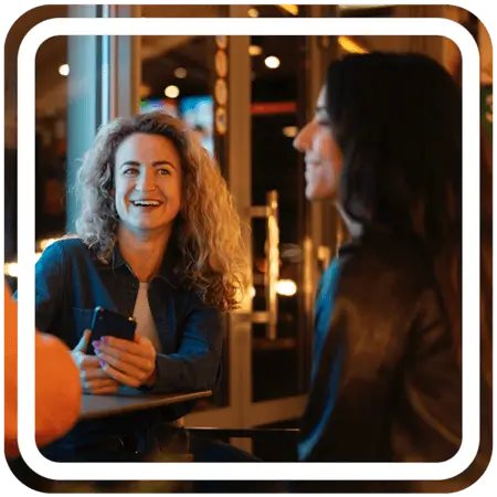 Two women inside a cafe smiling at each other