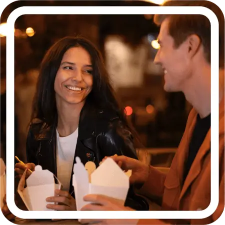 two people eatign chinese food and smiling at each other, possibly having a conversation