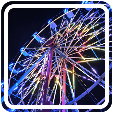 A brightly lit Ferris wheel spinning against a dark night sky.