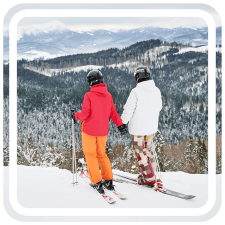 Two people holding each other's hands while skiing