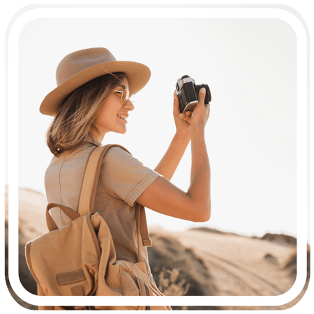 A tourist woman smiling while taking a picture with her camera