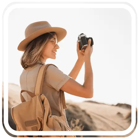 A tourist woman smiling while taking a picture with her camera