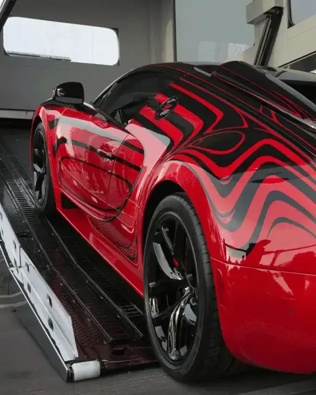 A red Bugatti Veyron being loaded onto a trailer