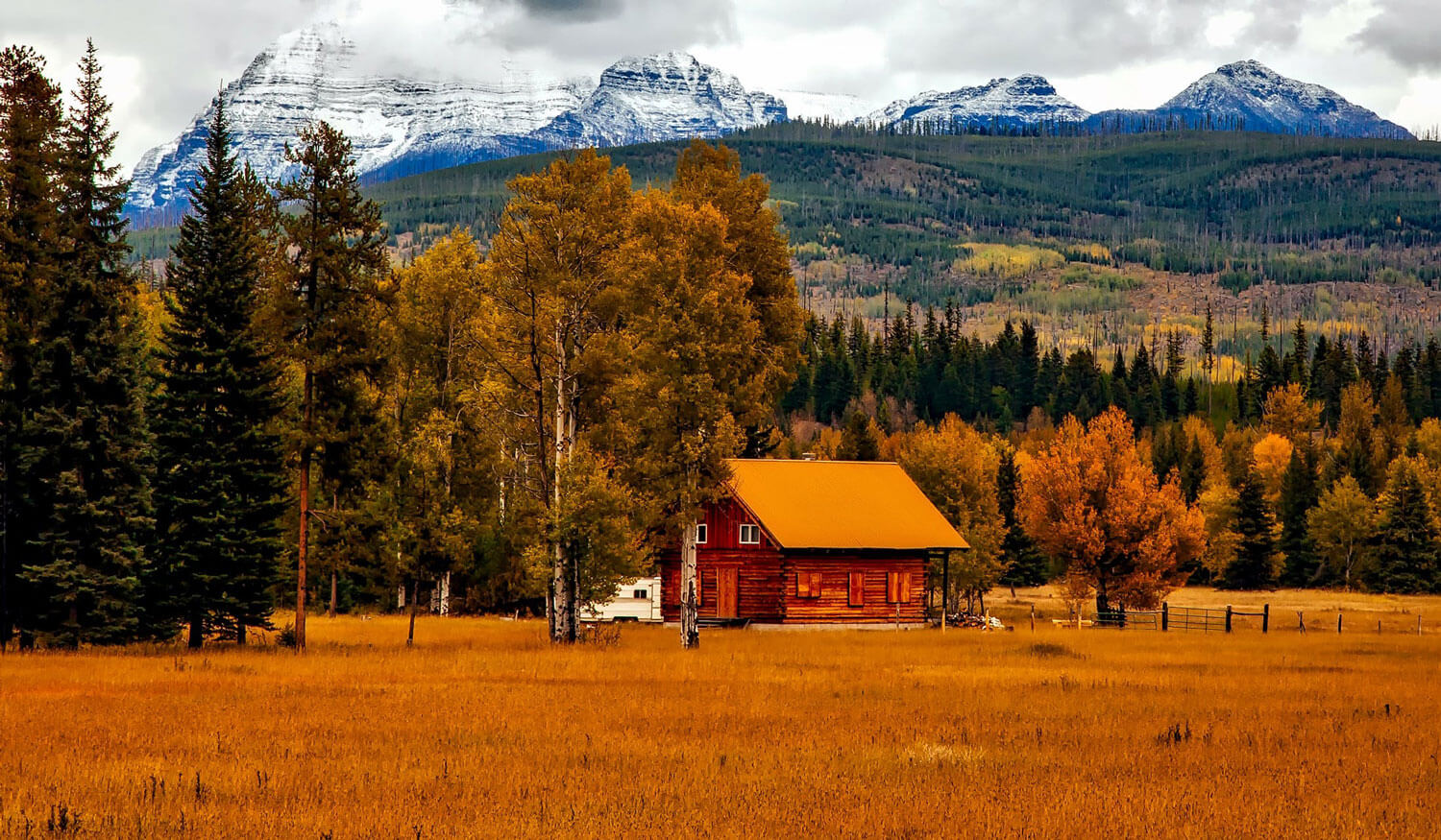 A log cabin nestled in a meadow, with the majestic peaks of the Rocky Mountains towering in the distance