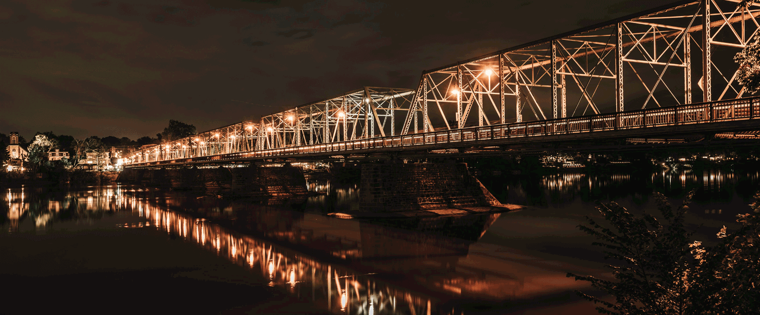 The New Hope-Lambertville Bridge, a six-span steel truss bridge illuminated at night